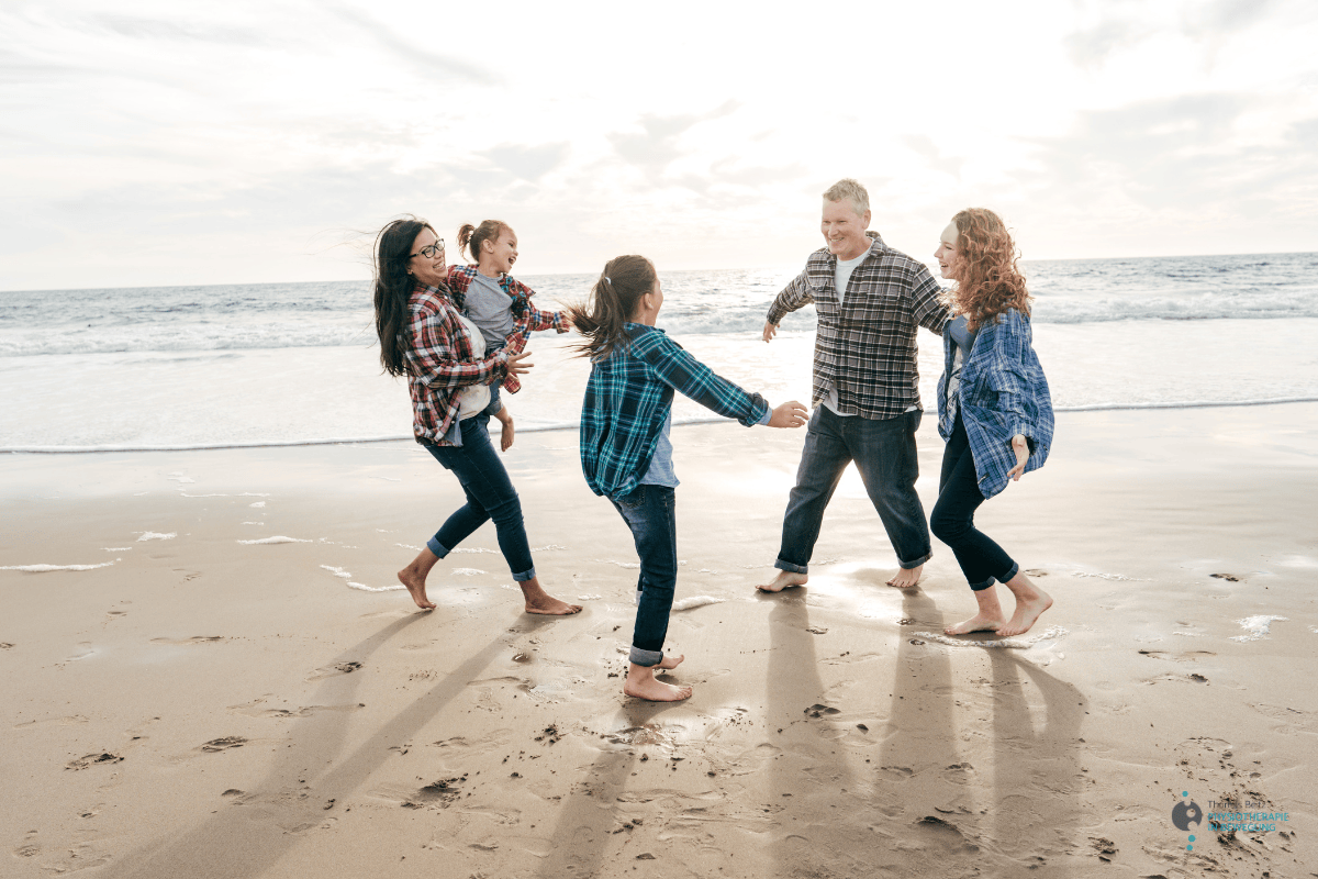 Personen stehen im Kreis aus Sand am Meer 